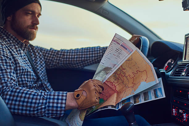 istock Young Man driver in car looking in to the map 509801890