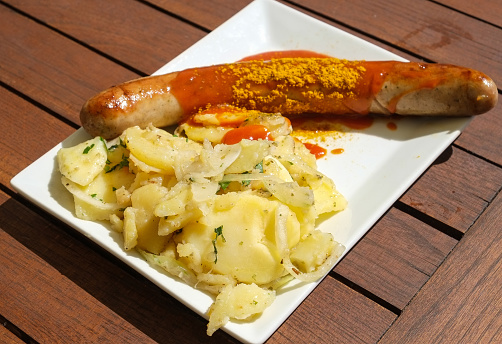 A currywurst sausage and potatoes with curry sauce