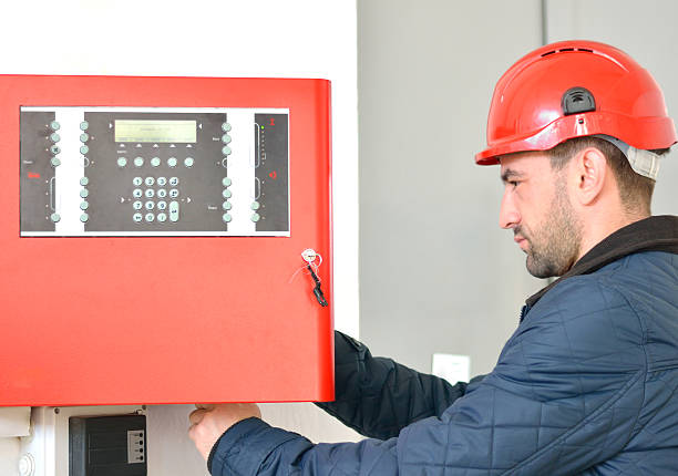 Electrician Wearing Hard Hat at Job Site Young attractive electrical engineer at work with a red helmet on his head furnace photos stock pictures, royalty-free photos & images