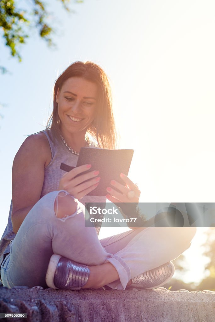 Happy woman with digital tablet Technology, lifestyle and people concept - smiling young woman or teenage girl with digital tablet or watching video in summer park. Adult Stock Photo