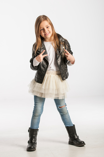 Beautiful little girl wearing a black leather jacket and posing in the studio