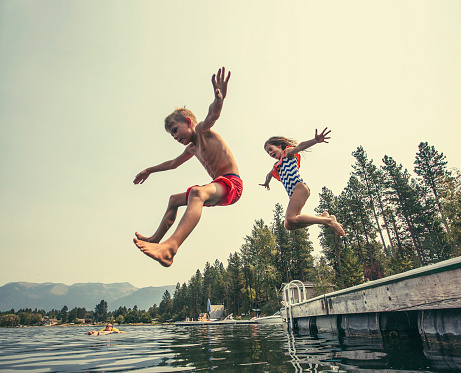 Los niños saltan de la el muelle en un hermoso lago de montaña photo