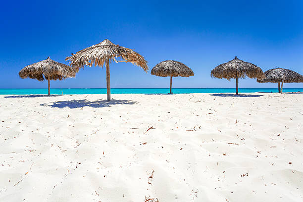 Beach Umbrellas made of palm leafs on the background of an exotic beach in Cayo Largo