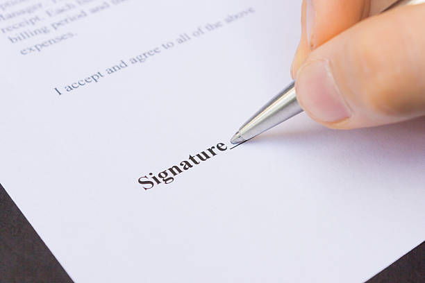 istock Fingers holding pen writing signature 509826539