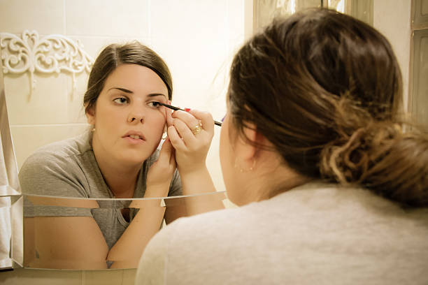istock Woman put eyeliner in front of a mirror 509846870