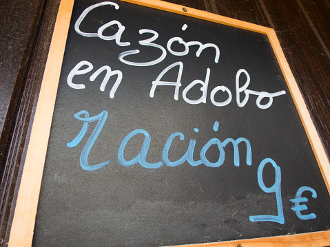 black placard spanish white handwritten in wall with typical menu food dishes in Spain restaurant like dogfish marinade