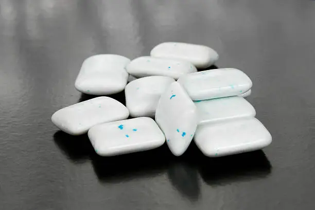 pieces of white chewing gum cushion with blue, peppermint particle