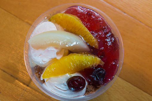 Ice cream and fruits in the plastic bowl on wooden floor background.