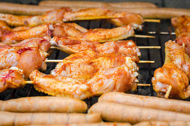 Raw pork sausages roasted on the grill, barbecue season outdoors. Meat roasting at barbecue. BBQ fresh beef.  kebab. Grill on charcoal and flame, picnic, street food. open flame BBQ. Garden party time