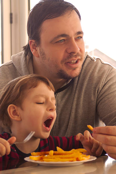 istock Father and Little Boy Eating Potato Chips 509861094