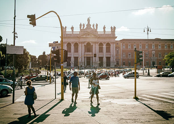 Rome, Italy - August 26, 2014: The Basilica of St. John in Lateran and its usual afternoon traffic jam. Some tourists cross the street.