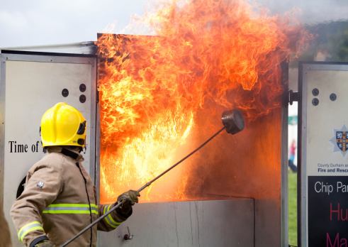 St. John's Chapel, England - August 30th, 2014: Safety demonstration by a fireman showing the effect of trying to put out a fire in a deep fryer pan using a cup of water.  Taken at the Weardale Show in the village of St. John's Chapel, County Durham, England.