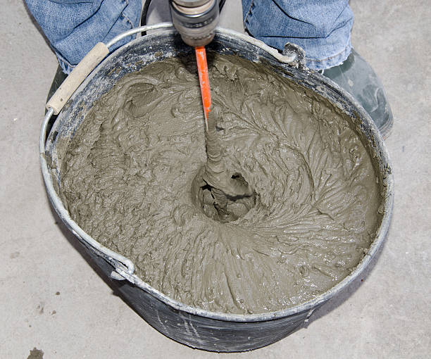 istock Tiler mixing tile adhesive with power drill in a bucket 509861329