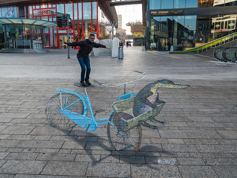 Almere, Netherlands - October 27, 2015: Unknown man shows the power of 3D optical illusion of a street painting by an unknown artist. Once a year the city allows artists to make paintings on the streets