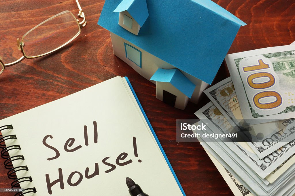 Sell house Notebook with the words Sell house  on the table. Selling Stock Photo