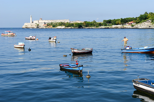 Havana, Cuba - 7 january 2016: Fisherman on his boat in the bay of Havana with El Morro castle in the background on the island of Cuba