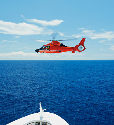 Rescue helicopter in sky at sea next to ship