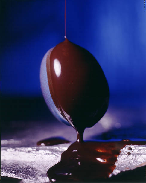 Egg Dipped in Chocolate Image of chocolate flowing down on studio photo blue egg silverstone stock pictures, royalty-free photos & images