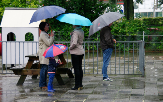 Brunssum, the Netherlands - August 26, 2014 : Parents waiting for there children on the first school-day of the new year. As you can see it is raining and the schoolyard is very wet.