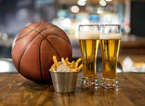 Watching a basketball game at a sports bar having drinks and eating snacks