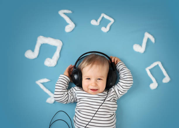 poco chico en azul de fondo con auriculares edredón - babies and children audio fotografías e imágenes de stock
