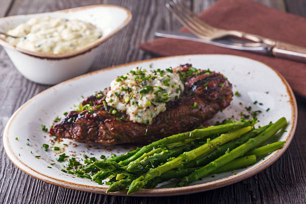 Steak with blue cheese sauce served with asparagus. Steak with blue cheese sauce served with asparagus on dark background. blue cheese stock pictures, royalty-free photos & images