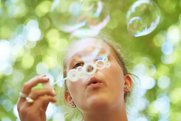 Cropped shot of a young woman blowing bubbles outside