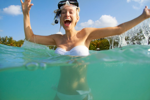 Portrait of an excited young woman in the ocean wearing snorkelling gear