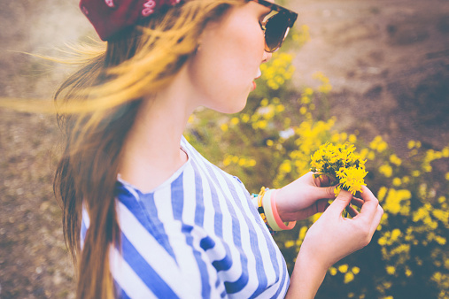 Girl holding a bunch of yellow wildflowers