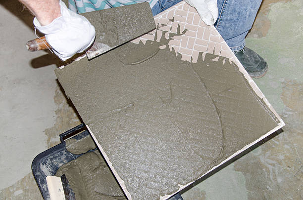 istock Tiler spreading tile adhesive on the back of a tile 509919017