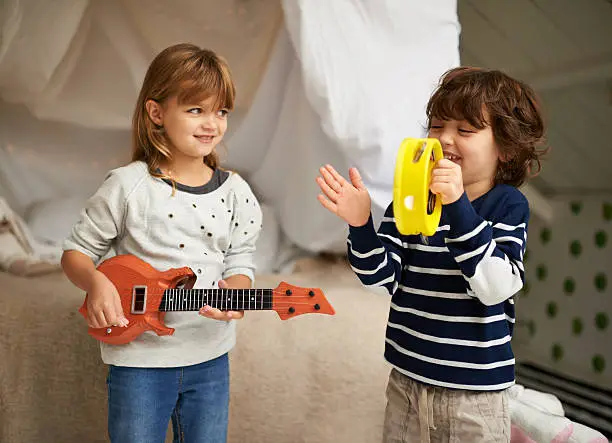 Shot of two adorable siblings playing with their musical toys