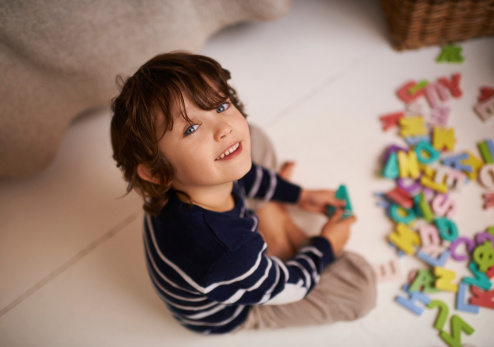 Portrait of an adorable little boy playing with colorful toy letters