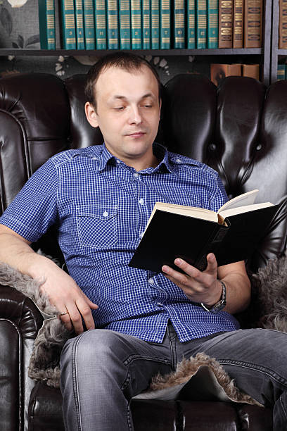 istock Young man sits in leather armchair and reads book 509919652