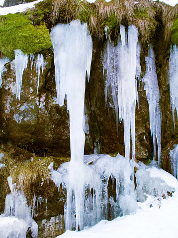 A wonderful image of icicles hanging from a rockface