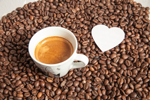 Heart and espresso cap on the dark coffee beans background