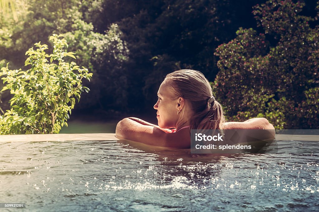 Woman relaxing in hotel  swimming pool looking at view Woman relaxing in private  swimming pool in luxury resort Hot Tub Stock Photo