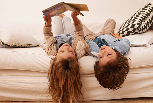 You can always get lost in a book Shot of two young children lying on their backs and reading a book together sibling stock pictures, royalty-free photos & images