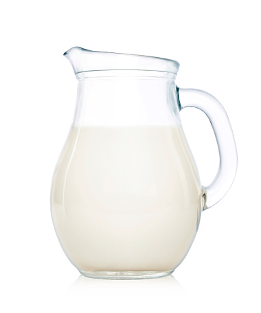 Glass jug of milk isolated on white background.