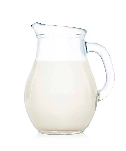 Glass jug of milk isolated on white background.