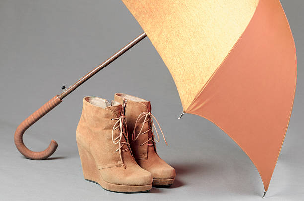 istock Brown suede boots under an umbrella on a gray background 509925300