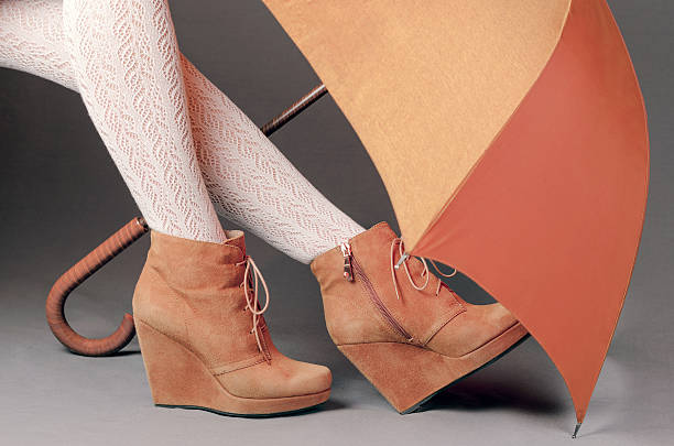 istock Female legs in brown suede boots under an umbrella 509929290