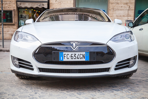 Rome, Italy - February 13, 2016 : White Tesla model S car parked on urban roadside in Rome, front view, closeup photo
