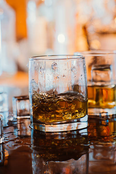 istock whiskey glass with ice and warm light on black table 509933230