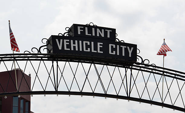 Flint Vehicle City sign Flint, MI, USA - August 22, 2015:  Flint Vehicle City sign, shown here on August 22, 2015, spans downtown Flint, MI. flint michigan stock pictures, royalty-free photos & images