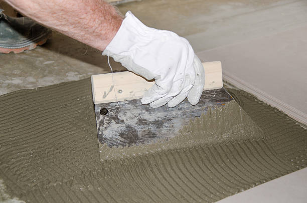 istock Tiler spreading tile adhesive on the floor 509956967