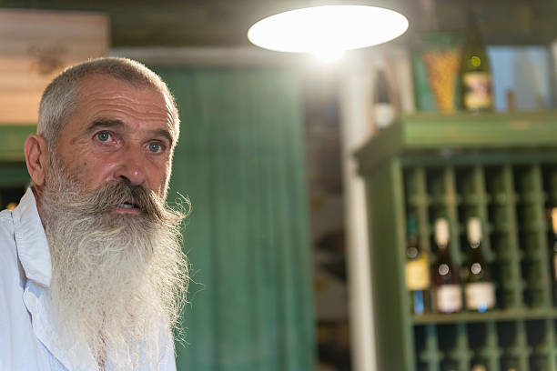Elderly winemaker's portrait, wine store in old cellar, Europe.