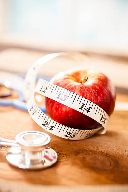 Photo of Apple a day keeps the doctor away.  Stethoscope, tape measure.