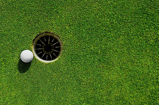 Into the hole Close up of a golf ball close to the hole putting green stock pictures, royalty-free photos & images