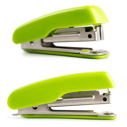 Two staplers with a different orientation, is bright green color, and isolated on a white background. Studio shot in macro mode, with a nice natural shadow.