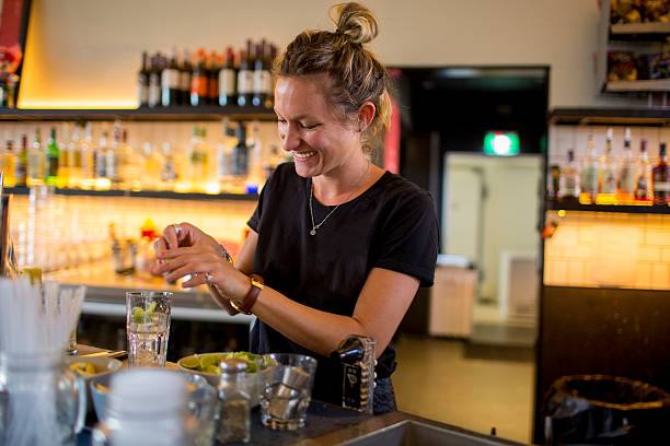 Female bar tender behind bar making a drink